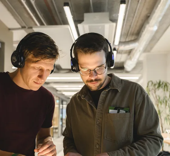 Two professionals wearing headsets work together in a contemporary office environment, demonstrating teamwork, communication, and workplace collaboration.