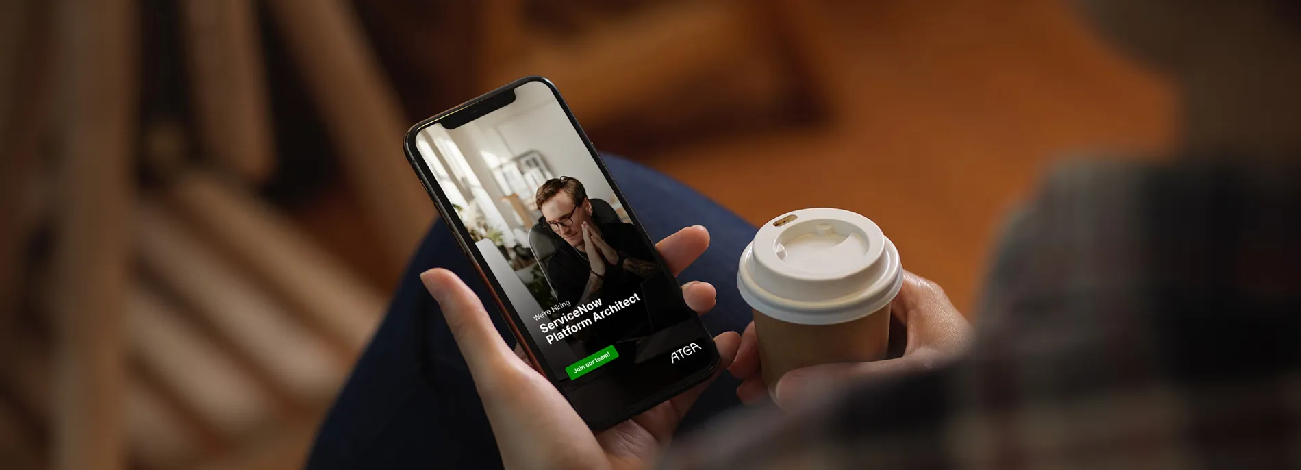 Smartphone displaying a open position, held in one hand alongside a takeaway coffee.